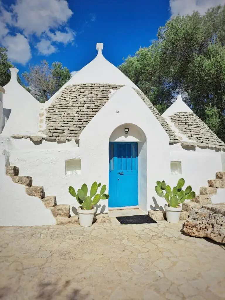 Beautiful traditional trullo house in Apulia with a blue door and conical roof.