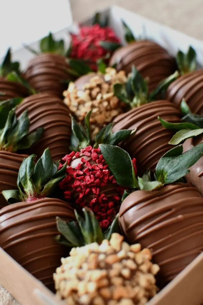 Tempting chocolate-covered strawberries with assorted toppings in a box.