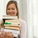 joven mujer con sus brazos cargados de libros