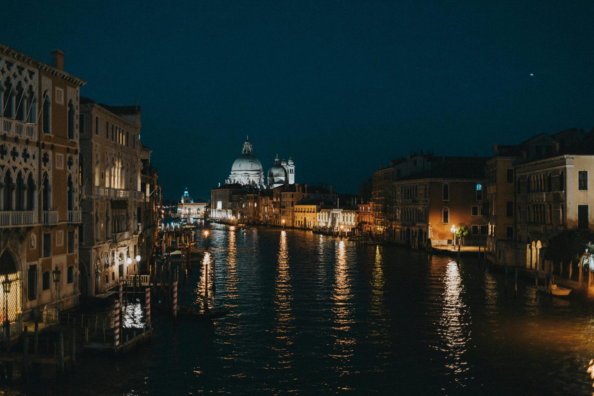Venecia al atardecer: lámparas cálidas reflejándose como oro líquido sobre los canales.
